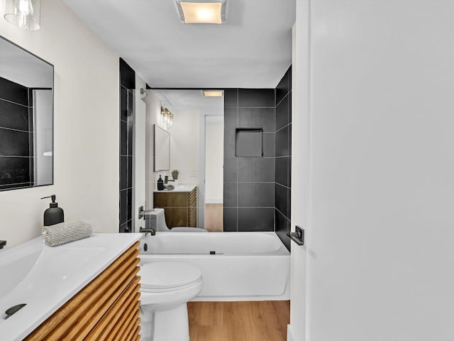 bathroom with toilet, shower / bath combination, wood finished floors, and vanity