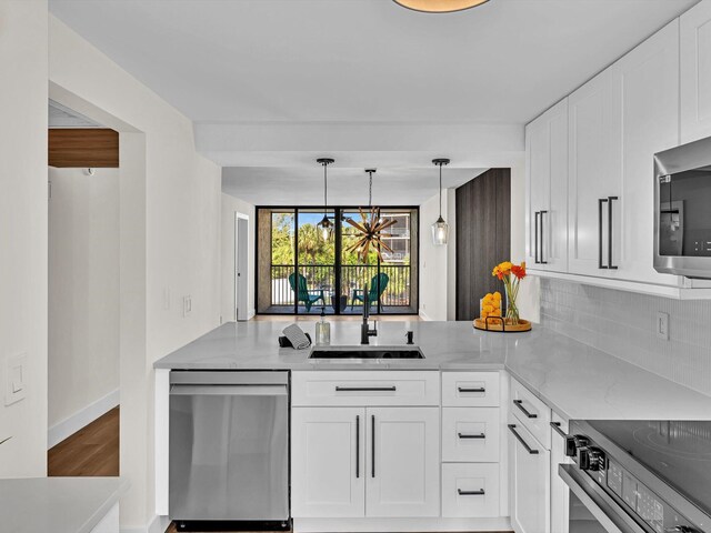 kitchen with light stone counters, backsplash, white cabinetry, a sink, and a wall of windows