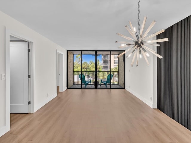 unfurnished room with a chandelier, a wall of windows, and light hardwood / wood-style flooring