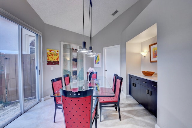 dining area featuring vaulted ceiling, a textured ceiling, and light tile patterned floors