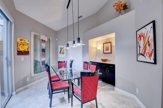 dining room with light tile patterned flooring, lofted ceiling, and a textured ceiling