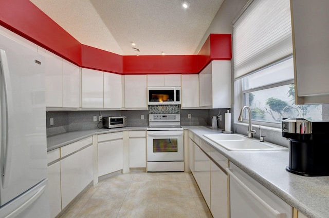 kitchen with sink, tasteful backsplash, light tile patterned floors, white appliances, and white cabinets