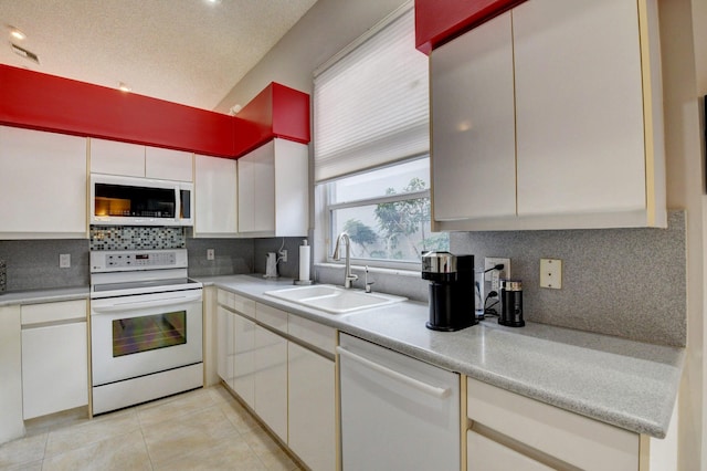 kitchen with white appliances, sink, light tile patterned floors, and white cabinets