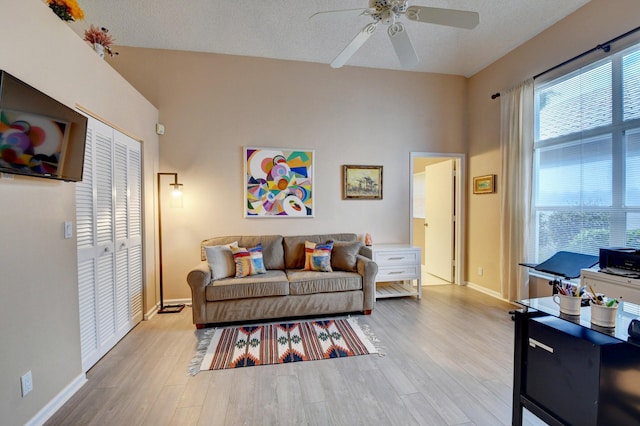 living room featuring ceiling fan, a textured ceiling, and light hardwood / wood-style flooring