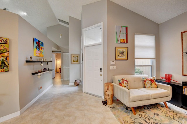 sitting room with light tile patterned flooring, vaulted ceiling, and a textured ceiling