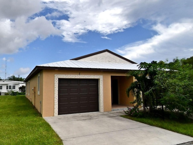 ranch-style house featuring stucco siding, concrete driveway, a front yard, metal roof, and a garage