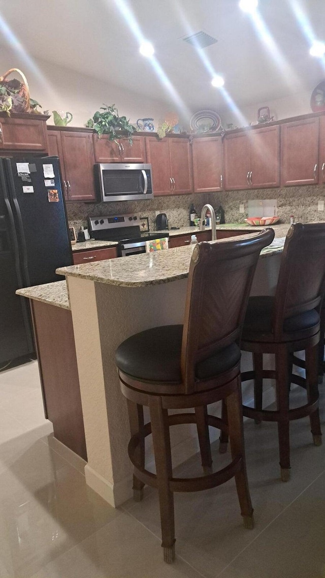 kitchen with a kitchen breakfast bar, stainless steel appliances, a kitchen island, and decorative backsplash