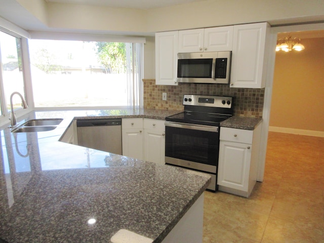 kitchen featuring sink, appliances with stainless steel finishes, dark stone countertops, tasteful backsplash, and white cabinets