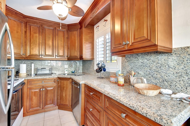 kitchen featuring sink, light stone counters, tasteful backsplash, light tile patterned floors, and appliances with stainless steel finishes