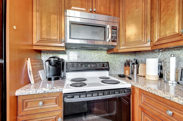 kitchen with backsplash, range with electric stovetop, and light stone countertops