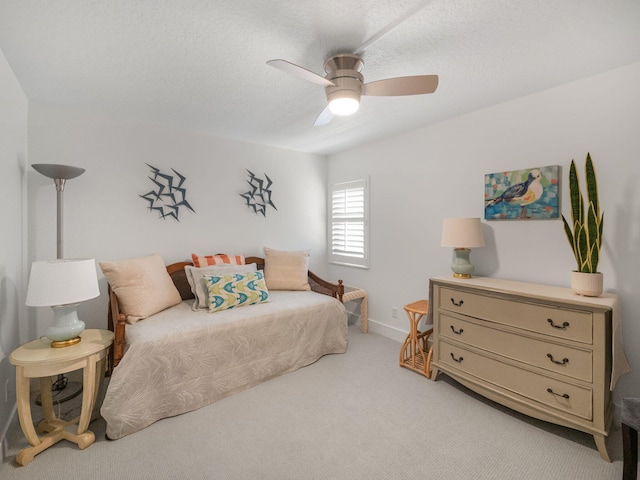 carpeted bedroom with ceiling fan and a textured ceiling