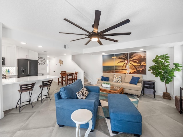 living room featuring ceiling fan and a textured ceiling