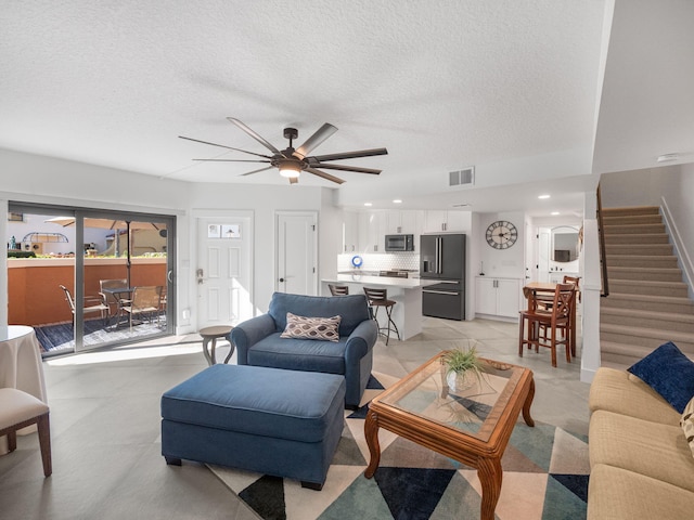 living room with a textured ceiling and ceiling fan