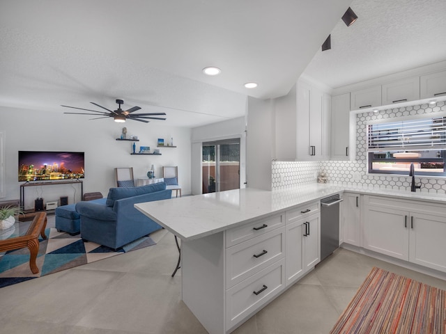 kitchen featuring sink, light stone countertops, kitchen peninsula, and white cabinets