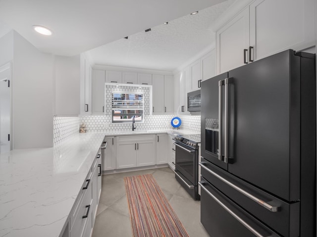 kitchen featuring black appliances, a textured ceiling, light stone countertops, decorative backsplash, and white cabinets