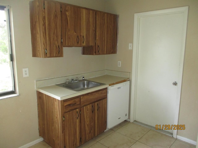 kitchen featuring sink, light tile patterned floors, and white dishwasher