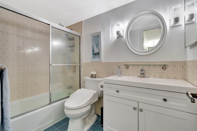 full bathroom featuring toilet, shower / bath combination with glass door, tile walls, vanity, and tile patterned flooring