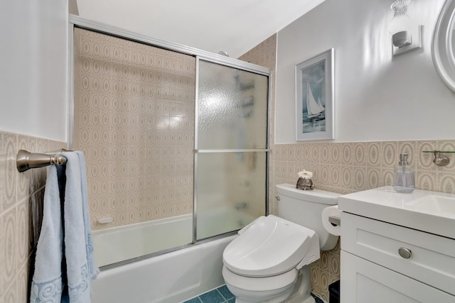 full bathroom with bath / shower combo with glass door, tile walls, vanity, and toilet