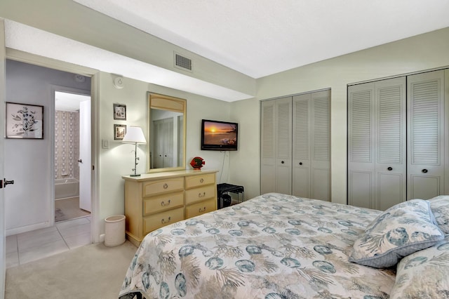 bedroom with multiple closets and light carpet