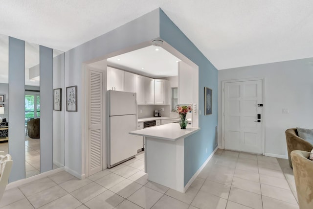 kitchen with white cabinetry, light tile patterned flooring, kitchen peninsula, and white refrigerator