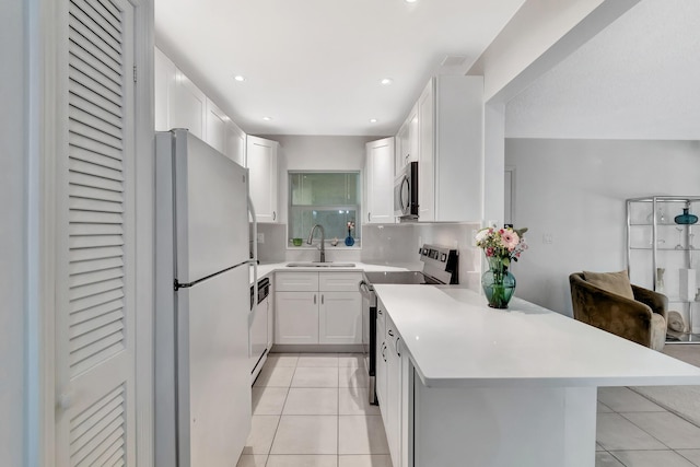 kitchen featuring light tile patterned flooring, appliances with stainless steel finishes, a breakfast bar, white cabinetry, and sink