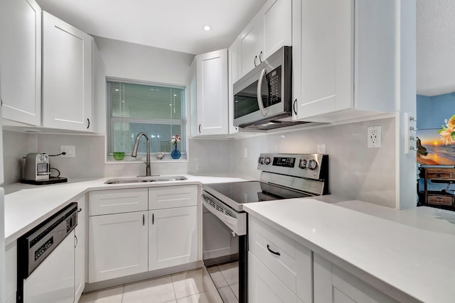 kitchen featuring light tile patterned floors, appliances with stainless steel finishes, sink, and white cabinets