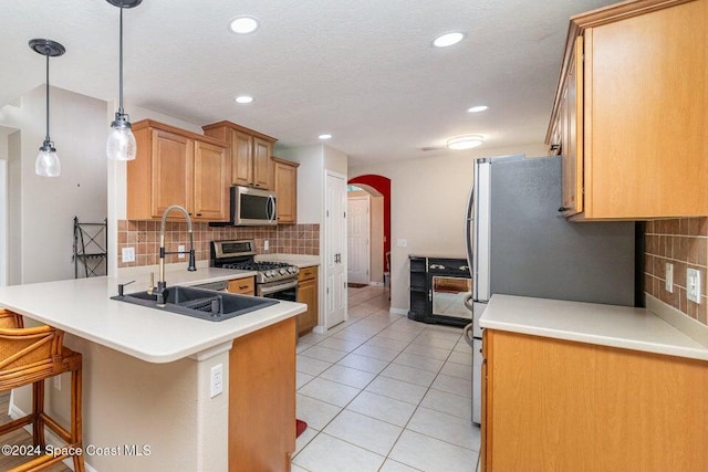 kitchen with light tile patterned floors, sink, a breakfast bar area, appliances with stainless steel finishes, and hanging light fixtures