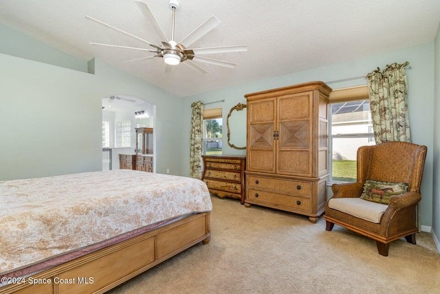 carpeted bedroom featuring ceiling fan, vaulted ceiling, multiple windows, and a textured ceiling