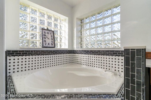 bathroom with plenty of natural light and tiled tub