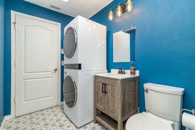 bathroom featuring stacked washer / dryer, toilet, and vanity