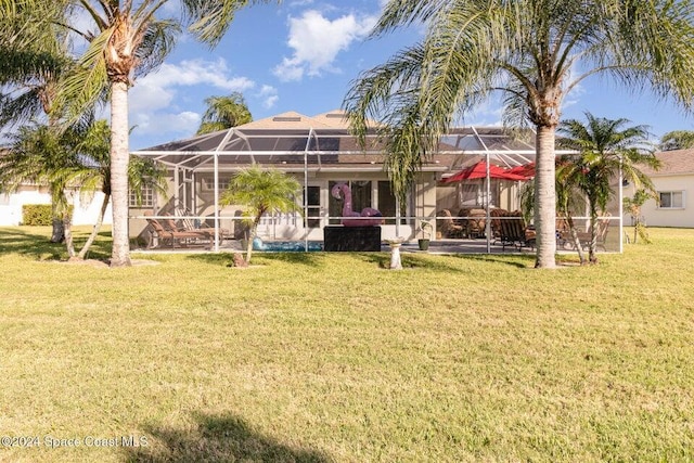 rear view of property featuring a lanai and a lawn