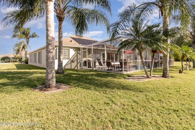 rear view of property with a yard, a patio area, and glass enclosure