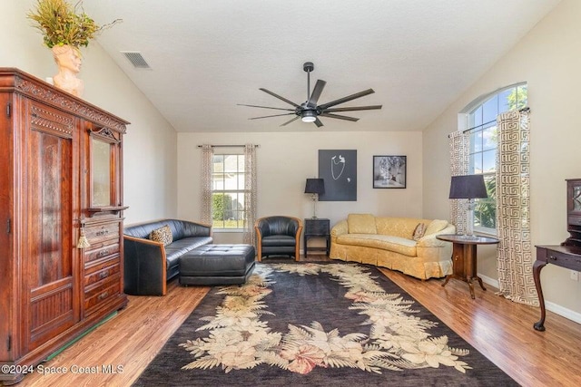 living room featuring vaulted ceiling, ceiling fan, light hardwood / wood-style floors, and a textured ceiling