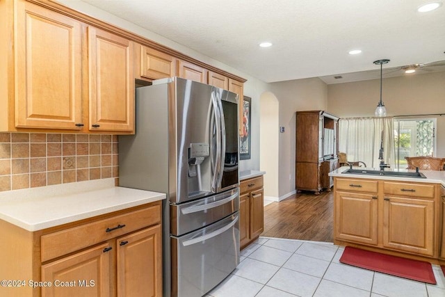 kitchen with stainless steel fridge, light tile patterned floors, hanging light fixtures, and backsplash