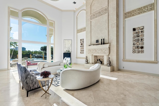 living room with a towering ceiling, ornamental molding, and a large fireplace