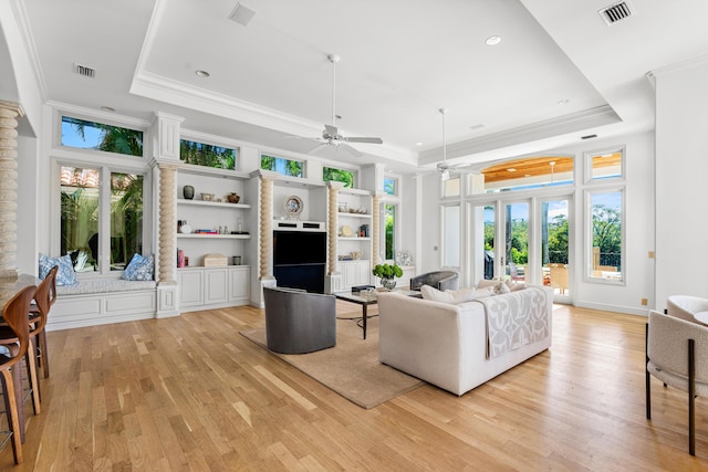 living room with ornamental molding, a raised ceiling, and light hardwood / wood-style floors