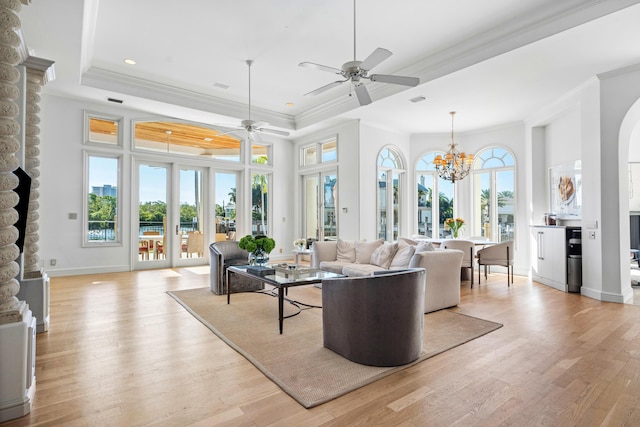 living room with crown molding, a tray ceiling, light hardwood / wood-style flooring, and french doors