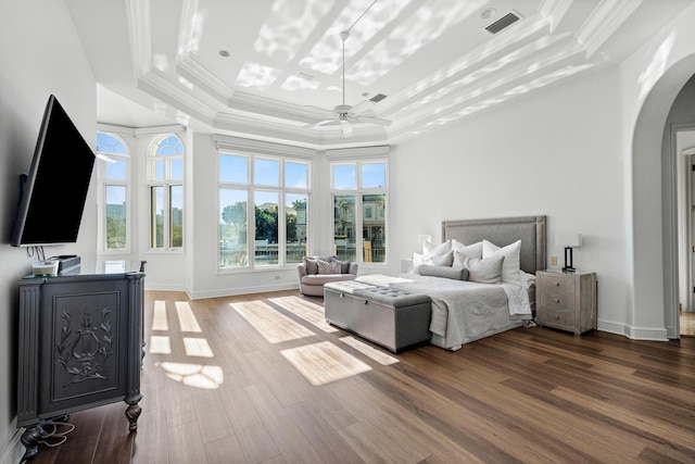 bedroom featuring hardwood / wood-style flooring, ornamental molding, ceiling fan, and a tray ceiling