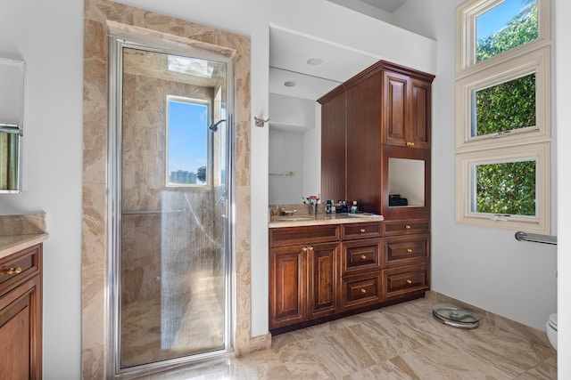 bathroom with vanity, toilet, a wealth of natural light, and a shower with shower door