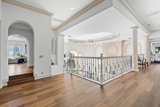 hallway featuring hardwood / wood-style flooring, crown molding, and decorative columns