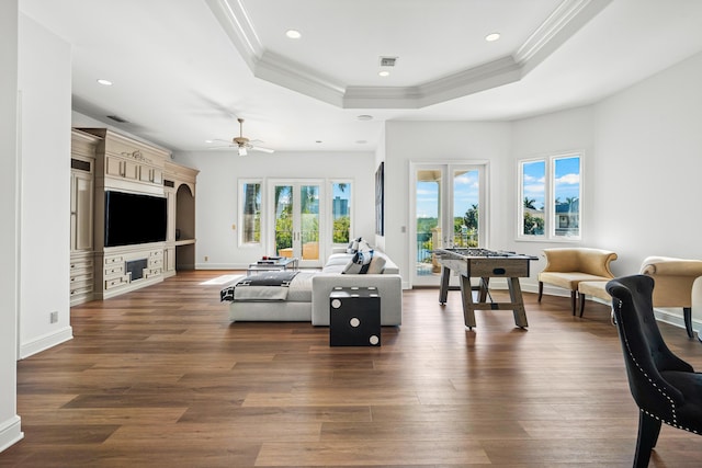 living room with dark hardwood / wood-style flooring, ornamental molding, french doors, and a raised ceiling