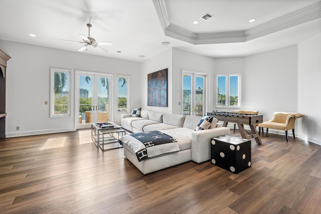 living room featuring french doors, ornamental molding, a tray ceiling, and dark wood-type flooring