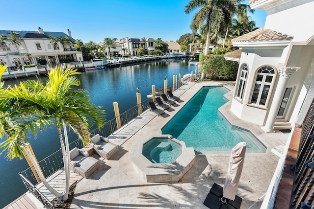 view of pool with an in ground hot tub, a water view, and a patio