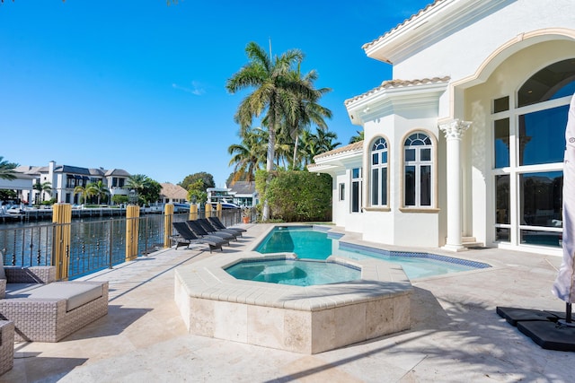 view of swimming pool featuring an in ground hot tub, a water view, and a patio area