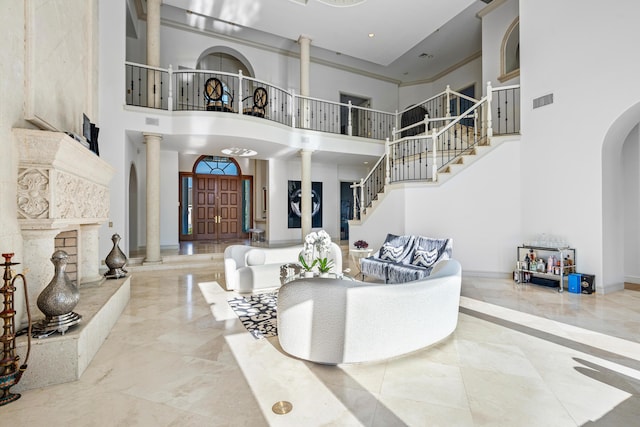 living room featuring crown molding, a towering ceiling, and ornate columns