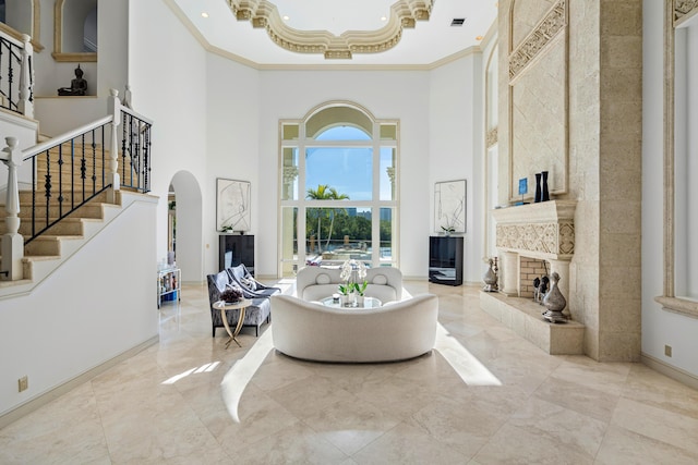 living room with a towering ceiling, a high end fireplace, and ornamental molding