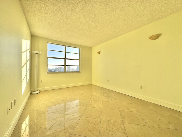 empty room with a textured ceiling and light tile patterned floors