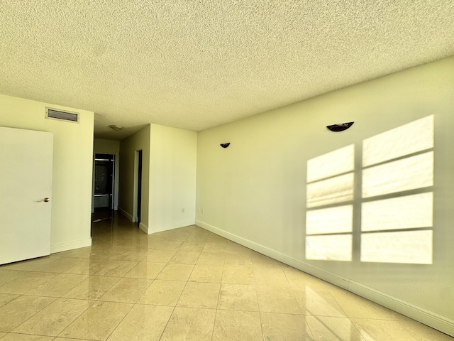 unfurnished room with a textured ceiling and light tile patterned flooring