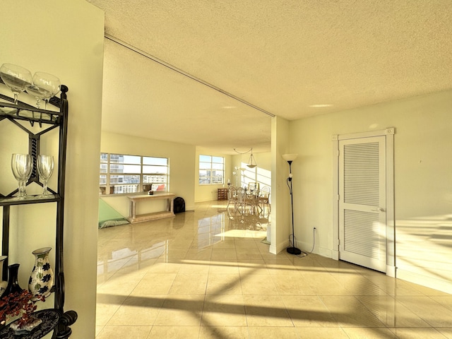 hall with a textured ceiling and light tile patterned flooring