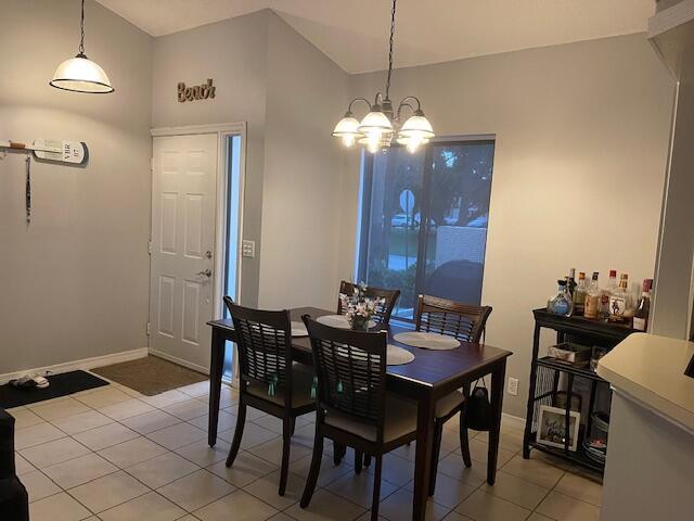 dining room featuring lofted ceiling, light tile patterned floors, and a notable chandelier